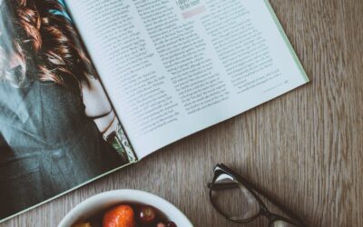 eyeglasses beside bowl of food and magazine on table